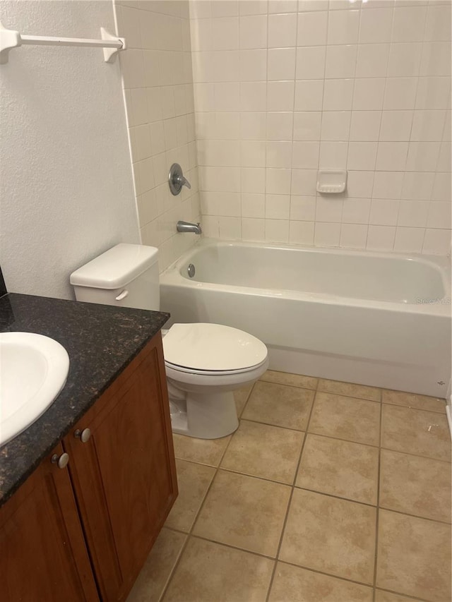 bathroom featuring a textured wall, toilet, vanity, shower / tub combination, and tile patterned floors