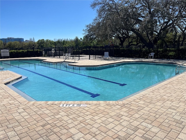 community pool with a patio area and fence