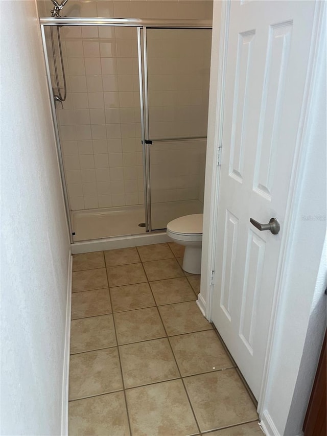 full bath with a stall shower, toilet, and tile patterned floors