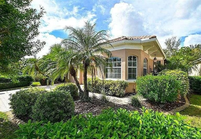 view of side of home featuring a tiled roof and stucco siding