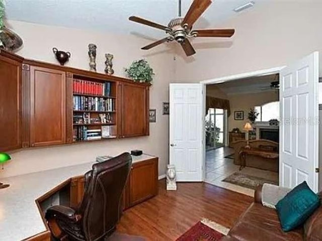 office space featuring visible vents, dark wood finished floors, ceiling fan, high vaulted ceiling, and built in desk