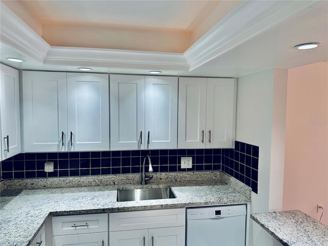 kitchen with backsplash, light stone counters, white dishwasher, white cabinetry, and a sink