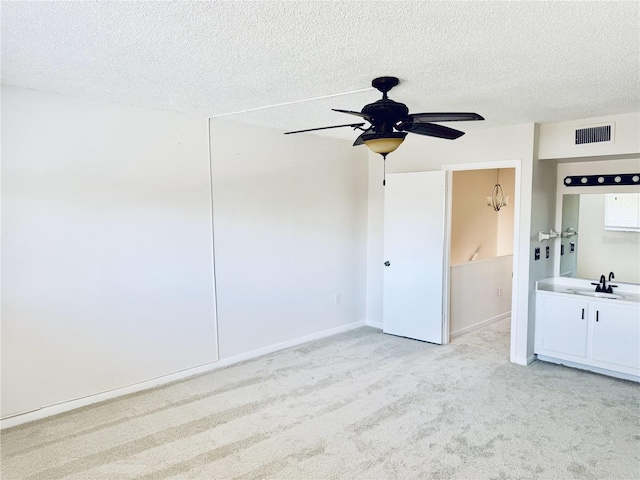 unfurnished bedroom with visible vents, baseboards, light colored carpet, a textured ceiling, and a sink