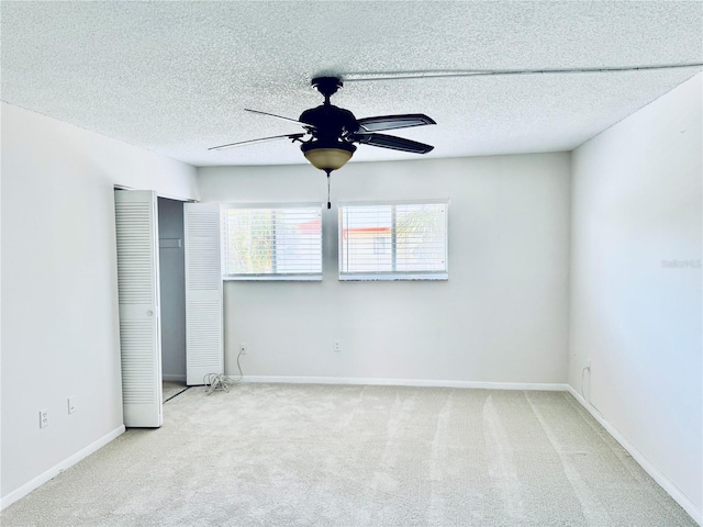 unfurnished room with baseboards, ceiling fan, a textured ceiling, and carpet