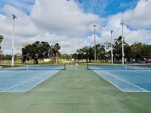 view of tennis court featuring community basketball court and fence