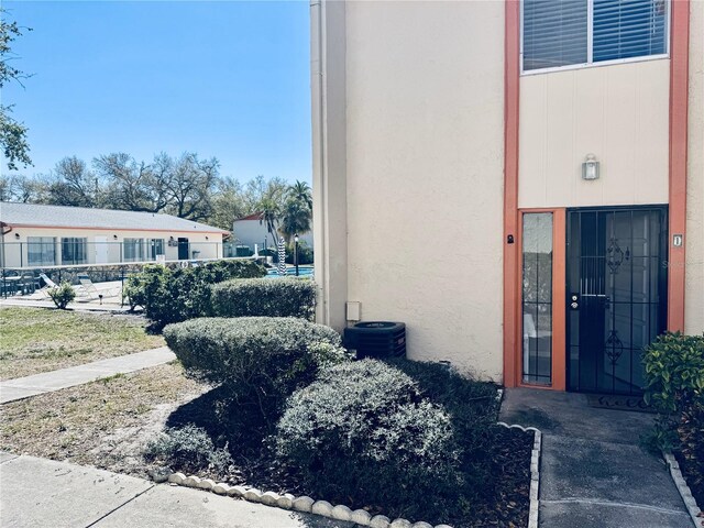 view of exterior entry with central air condition unit and stucco siding