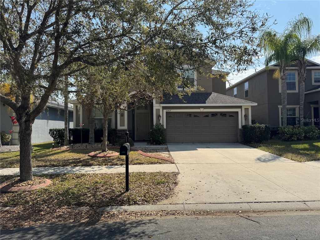 traditional home with an attached garage, driveway, and stucco siding