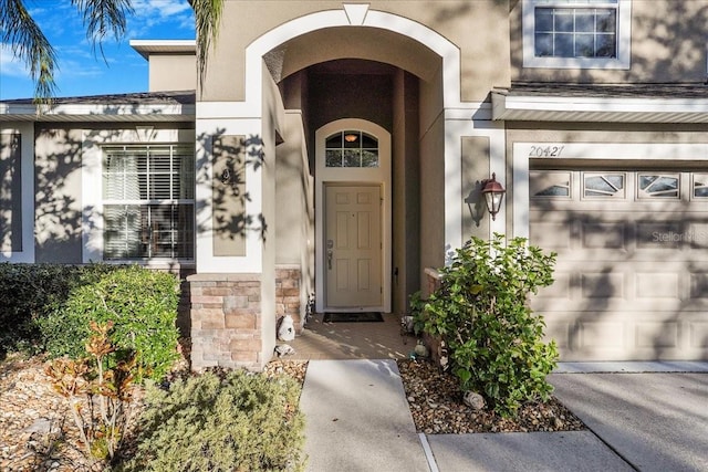 view of exterior entry featuring stucco siding and stone siding