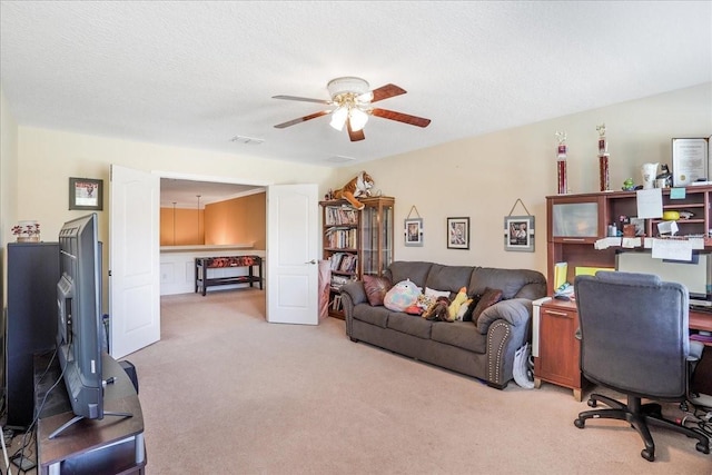 living area featuring light carpet, visible vents, a textured ceiling, and a ceiling fan