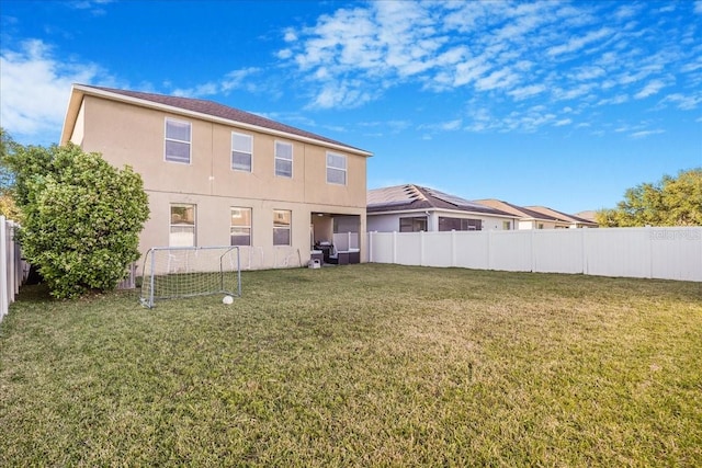 rear view of house featuring stucco siding, a lawn, and fence