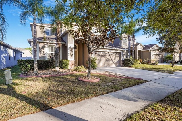 view of front of property featuring a front yard, a garage, driveway, and stucco siding