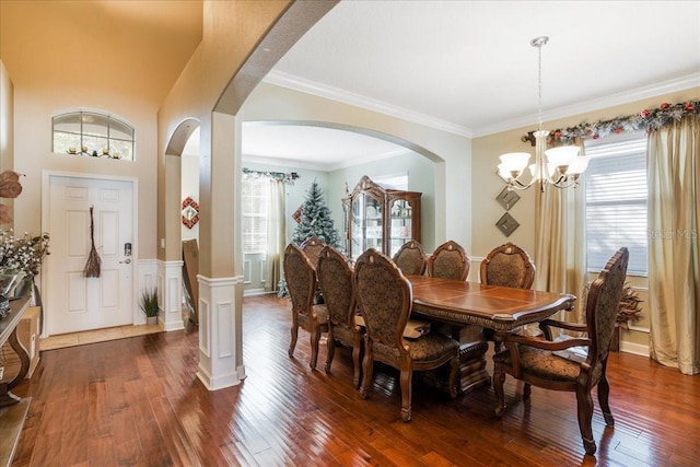 dining room featuring a wealth of natural light, a notable chandelier, arched walkways, and dark wood-style flooring