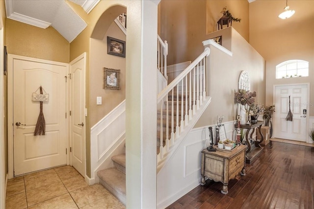 entrance foyer featuring stairway, a decorative wall, and a wainscoted wall