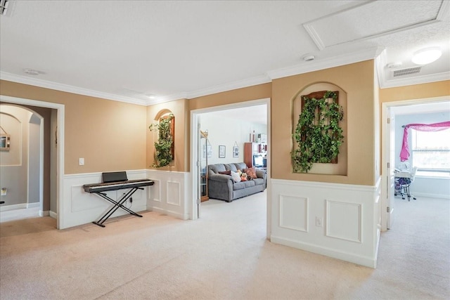 corridor with visible vents, carpet, wainscoting, crown molding, and attic access