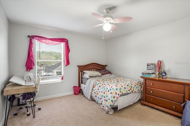 bedroom featuring a textured ceiling, light colored carpet, baseboards, and ceiling fan