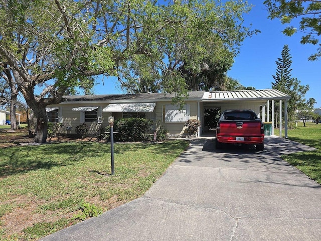 ranch-style home with a front yard, metal roof, a carport, driveway, and a standing seam roof