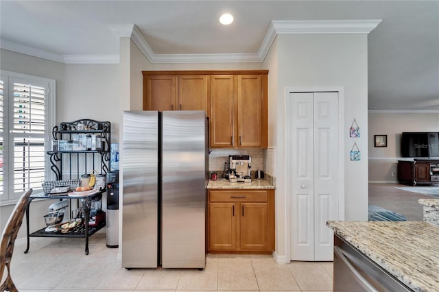 kitchen with tasteful backsplash, light stone countertops, ornamental molding, brown cabinets, and appliances with stainless steel finishes