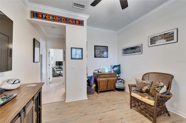 sitting room with visible vents, baseboards, ornamental molding, light wood-style floors, and a ceiling fan