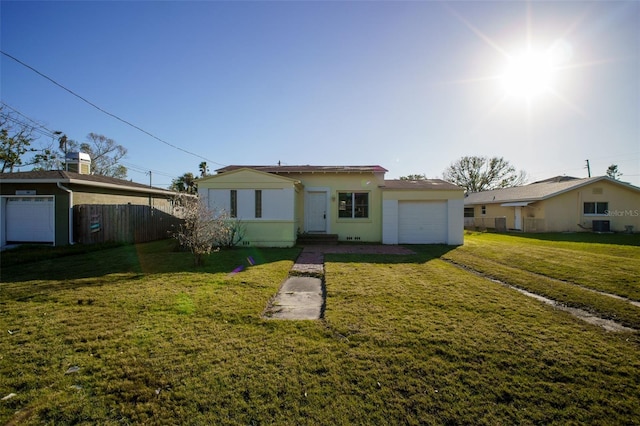 ranch-style house featuring an attached garage, fence, central air condition unit, a front yard, and stucco siding