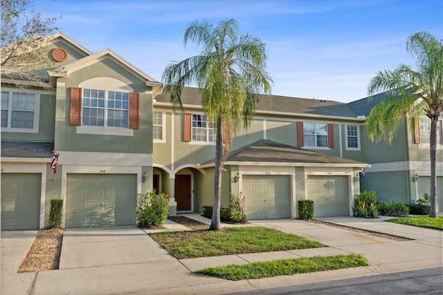 townhome / multi-family property with driveway, a garage, and stucco siding