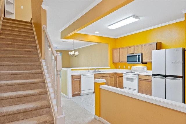 kitchen with a peninsula, white appliances, ornamental molding, and light countertops