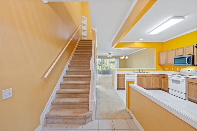 kitchen with light countertops, ornamental molding, a sink, white appliances, and a peninsula