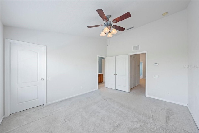 unfurnished bedroom featuring light colored carpet, visible vents, vaulted ceiling, ceiling fan, and baseboards