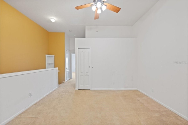 unfurnished room with baseboards, ceiling fan, and light colored carpet