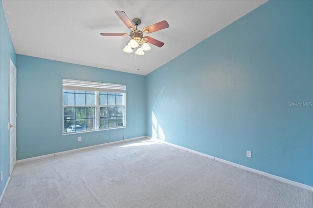 carpeted empty room featuring a ceiling fan and baseboards