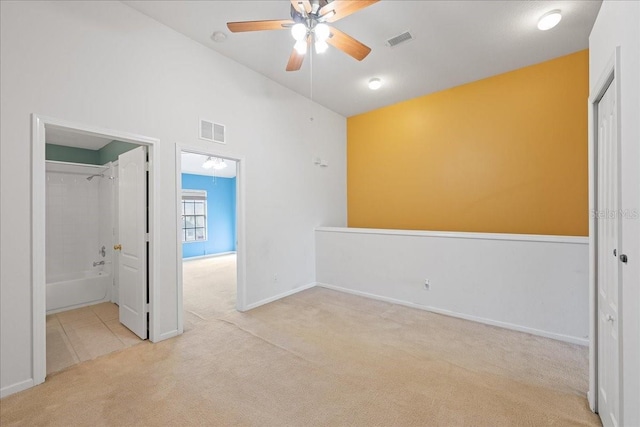 carpeted spare room featuring a ceiling fan, lofted ceiling, visible vents, and baseboards