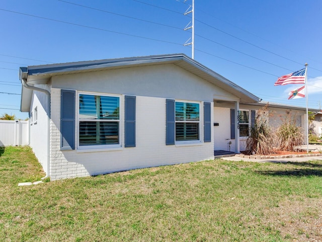 ranch-style home with brick siding, fence, and a front lawn