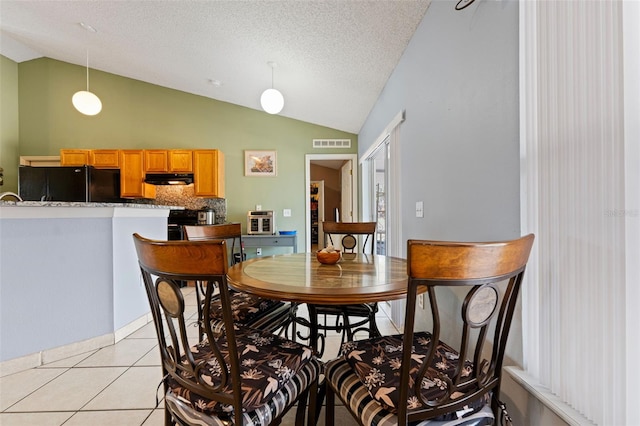 dining room with light tile patterned floors, visible vents, a textured ceiling, and lofted ceiling