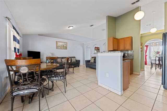 kitchen with lofted ceiling, light tile patterned floors, and arched walkways