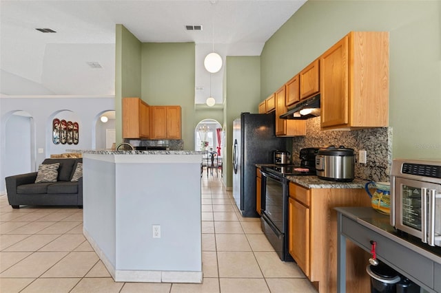 kitchen with light tile patterned floors, visible vents, arched walkways, and black range with electric cooktop