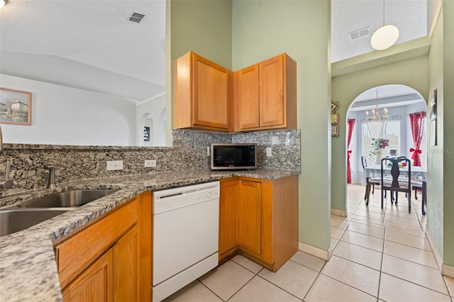 kitchen featuring visible vents, lofted ceiling, arched walkways, dishwasher, and tasteful backsplash