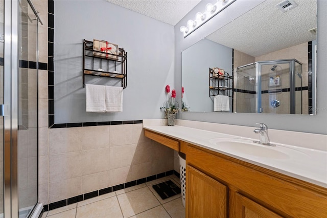 bathroom with tile patterned flooring, visible vents, a shower stall, tile walls, and a textured ceiling