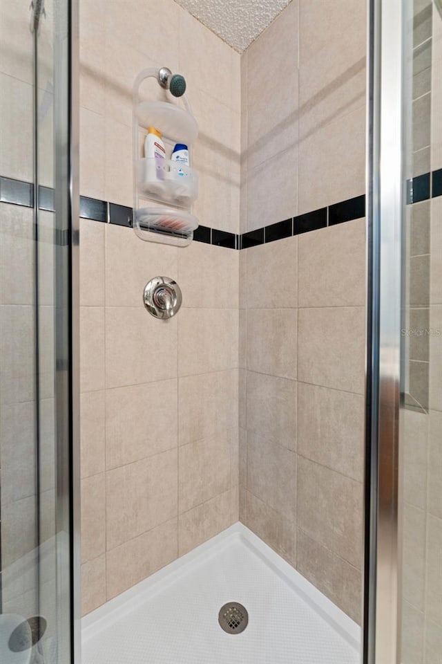 bathroom with a shower stall and a textured ceiling