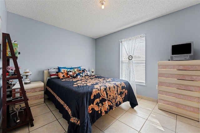 bedroom featuring baseboards, a textured ceiling, and light tile patterned flooring