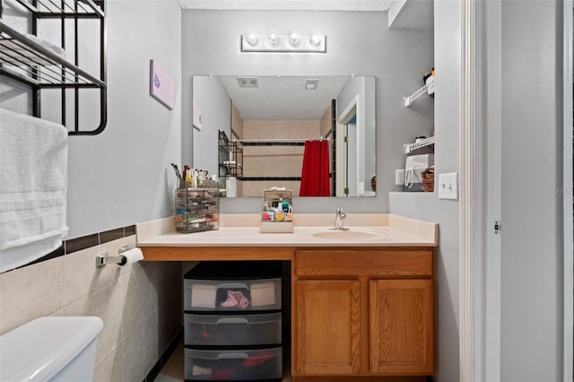 bathroom with vanity, visible vents, a textured ceiling, tile walls, and toilet