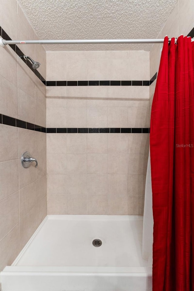 full bath featuring a stall shower and a textured ceiling