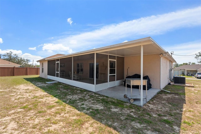 rear view of house featuring stucco siding, fence, a yard, a sunroom, and central AC unit