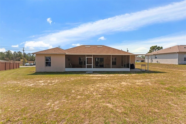 back of property featuring stucco siding, a yard, and a sunroom