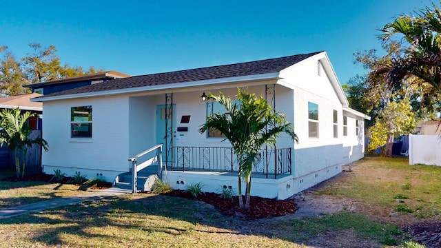 view of front facade featuring crawl space, covered porch, roof with shingles, and a front yard