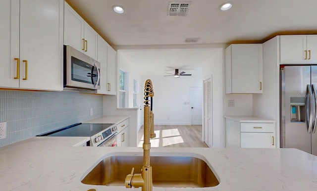 kitchen featuring stainless steel appliances, white cabinetry, visible vents, and decorative backsplash