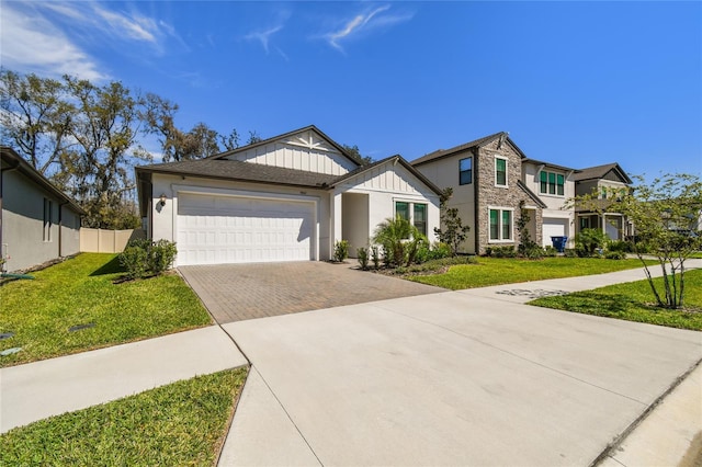 view of front of property with decorative driveway, an attached garage, board and batten siding, and a front yard