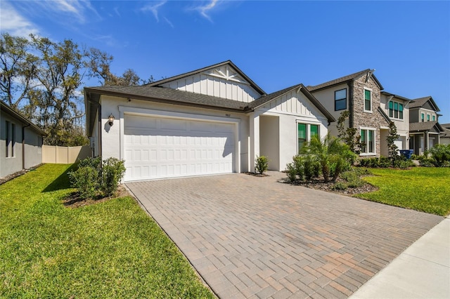 view of front of house with board and batten siding, a front yard, decorative driveway, stone siding, and an attached garage