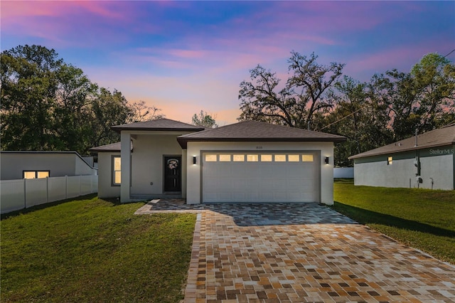 view of front of property with an attached garage, fence, decorative driveway, stucco siding, and a front yard