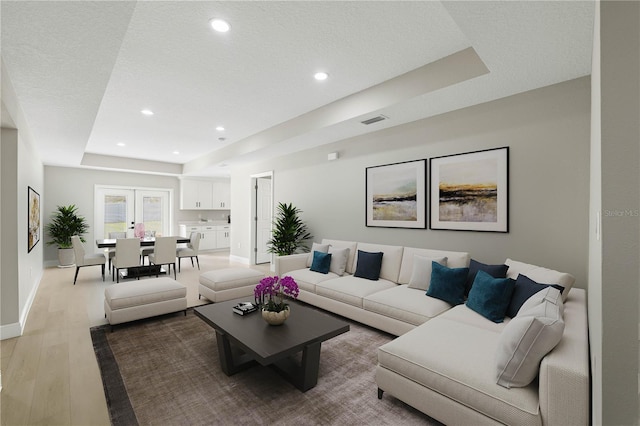 living area featuring recessed lighting, a raised ceiling, visible vents, light wood-style floors, and baseboards