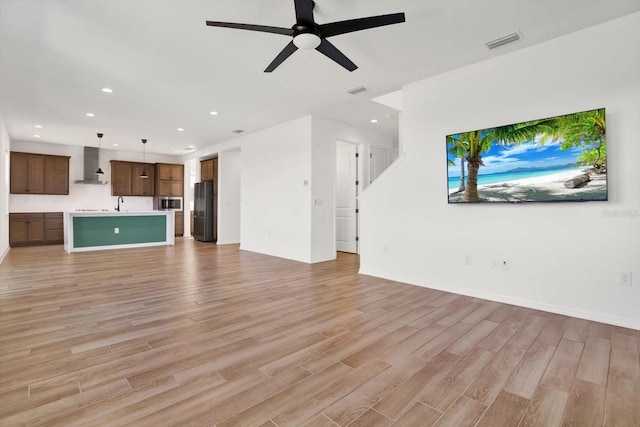 unfurnished living room with visible vents, a ceiling fan, recessed lighting, light wood finished floors, and baseboards