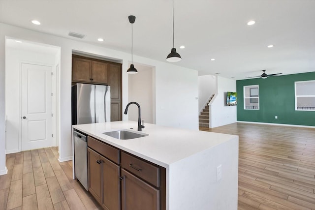 kitchen featuring visible vents, pendant lighting, appliances with stainless steel finishes, light wood-style floors, and a sink